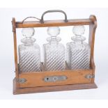 A 1930's oak three bottle Tantalus The carved and bound outer case,