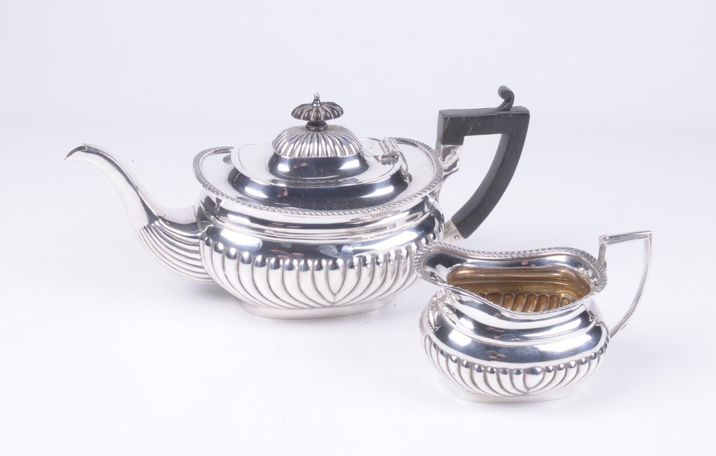 A Victorian silver tea pot and milk jug Of ovoid form, with an embossed fluted lower body,