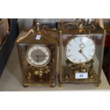 Two vintage German anniversary clocks, with revolving pendulums, within glazed brass cases.