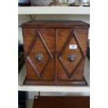 An Edwardian oak smokers cabinet, the twin hinged doors enclosing a fitted interior,