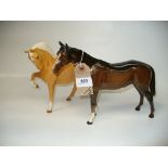 A Beswick model of a bay horse and a Beswick matt model of a palomino horse, right leg raised.