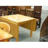 A Modern ash drop leaf dining table on legs of square section.