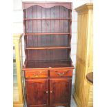 A modern stained pine high back dresser with three enclosed shelves above two short drawers and two