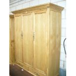 A Light oak French style triple wardrobe with a cavetto cornice above three panelled cupboard doors