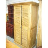A Light oak French style wardrobe with two louvre doors raised on a plinth base.