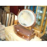 A 19th Century mahogany oval toilet mirror on a bowfront plinth with a single frieze drawer.