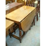 An 18th Century oval oak drop leaf dining table on ring turned baluster supports.