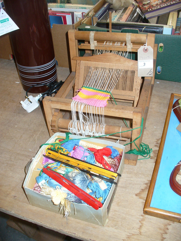 A Miniature loom and a collection of wools.