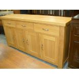 A Contemporary light oak sideboard with three drawers over four cupboard doors each with brushed