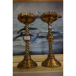 A pair Gothic style brass candlesticks raised on barley twist stems.