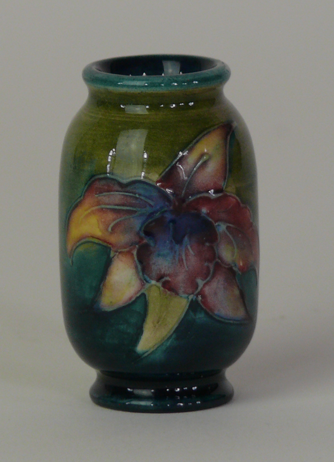 A Walter Moorcroft miniature vase of cylindrical form Decorated in the 'Orchid' pattern on a green