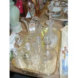 Two bulbous glass decanters, cruet bottles and other glass ware to a tray.