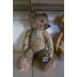 A pre-war gold plush Merrythought teddy bear, with glass button eyes, button to left ear,