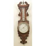 A late Victorian oak cased wall barometer The white circular dial below glazed mercury thermometer,