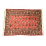 A Bokhara style rug Of rectangular form with tasselled edging, the vibrant red ground,