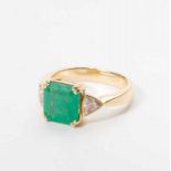 An 18 carat gold ring with diamond and emerald Circa 1990 The gold set ring set with a central