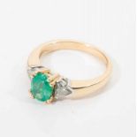 An 18 carat gold ring with diamond and emerald 20th century The gold ring set with an oval facetted