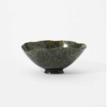 A large nephrite bowl On oval foot, the high bowl with sculpted rim, the stone a clear green colour