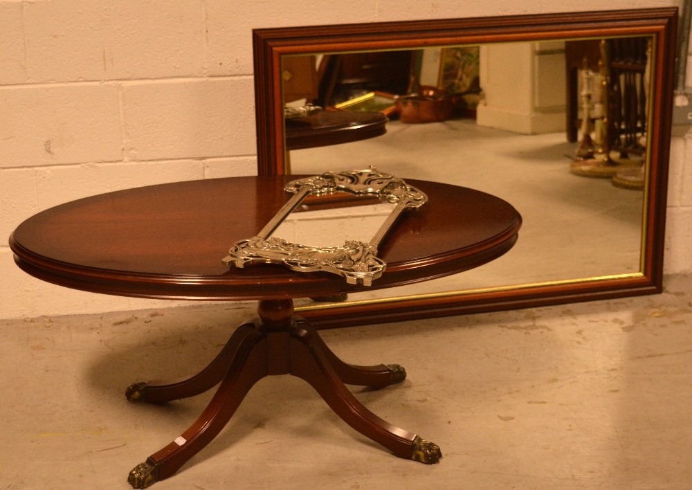 A reproduction mahogany oval coffee table, raised on quadripartite base to hairy paw feet,