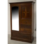 An Edwardian mahogany combination wardrobe with a single mirrored door opening to reveal near