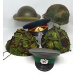 Four mid-20th century military helmets, three with camouflage covers and liners,
