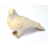 An early 20th century carved ivory bird with mother of pearl set eyes, length 10cm (af).