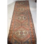 An Eastern burnt orange ground geometric pattern runner, 296 x 84cm.