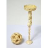 An early 20th century heavily carved ivory five globe puzzle ball raised on a figural pedestal