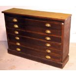 A cabinet with six long drawers and brass handles, each with 'GR' insignia to the handles,