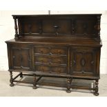 A 1920s oak sideboard with a carved panel and upstand supported by two turned columns,