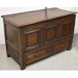 An 18th century oak blanket box with carved frieze above three raised panels over two drawers to