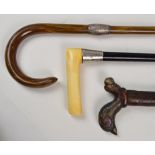 Three walking sticks; an ebonised example with hallmarked silver collar and horn handle,