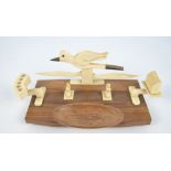 A 1930s ivory and mahogany smokers' stand decorated with a carved model of a bird in flight,