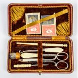 An Edwardian Moroccan leather cased sewing kit with bone handled implements and a hallmarked silver