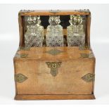 An Edwardian oak and electroplated mounted combination tantalus/smokers' compendium housing three