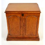 An Edwardian oak stationery cabinet enclosing drawers and pigeon holes with front flap leather