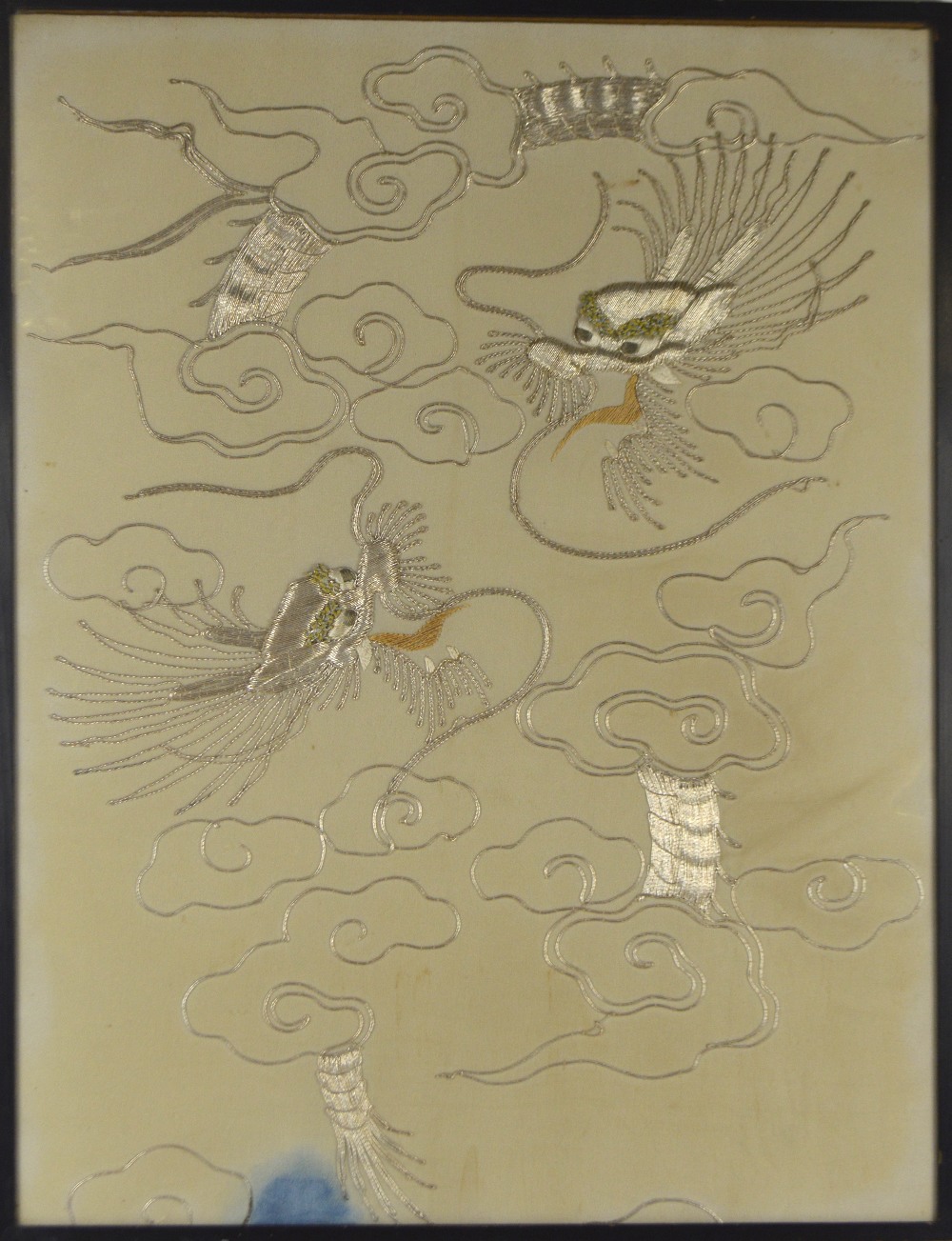 A large 20th century Chinese silk embroidery depicting two confronting dragons amongst clouds,