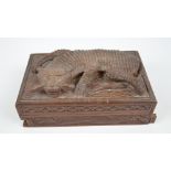 An Anglo-Indian carved wooden cigarette puzzle box carved in relief with a tiger to the hinged lid