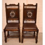 A pair of oak wheel back chairs with multiple turned spindle supports.