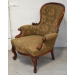 A Victorian walnut spoon back armchair upholstered in green floral fabric.