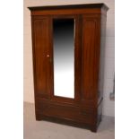 An Edwardian wardrobe with mirrored door and one large lower drawer.