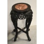 A Chinese heavily carved hardwood jardinière stand, the circular top inset with veined pink marble,