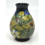 A Moorcroft vase, tube-line decorated with fuchsias and other flora against a dark green ground,