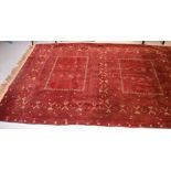 A red ground Middle Eastern rug with geometric design, fringed at one end, approx 272 x 170cm.