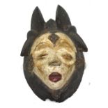 An early 20th century African Dan tribe wall mask, carved in relief with a female head,