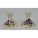 A pair of Moorcroft squat candlesticks, tube-line decorated with clematis over a cream ground,