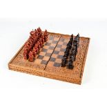 A 20th century Balinese wooden chess set with board, boxed.