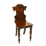 An early Victorian mahogany shield back hall chair carved with foliate scroll motifs,