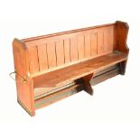 A pitch pine pew with panel back and canted seat, with umbrella stand loop to one side, width 183cm.