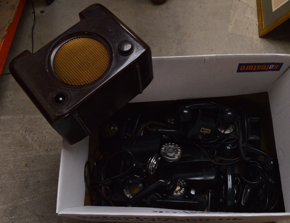 A collection of ten vintage black telephones in various states of disrepair and a brown bakelite